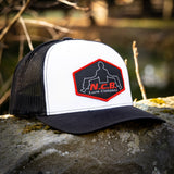 A black/white NCB patch style snapback hat positioned on a rock